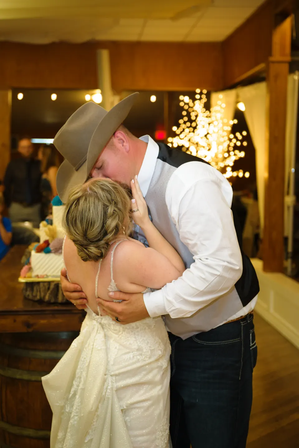 Novio de sombrero vaquero besando a la novia durante la recepción en el Kosciusko Community Hall en Kosciusko, Texas