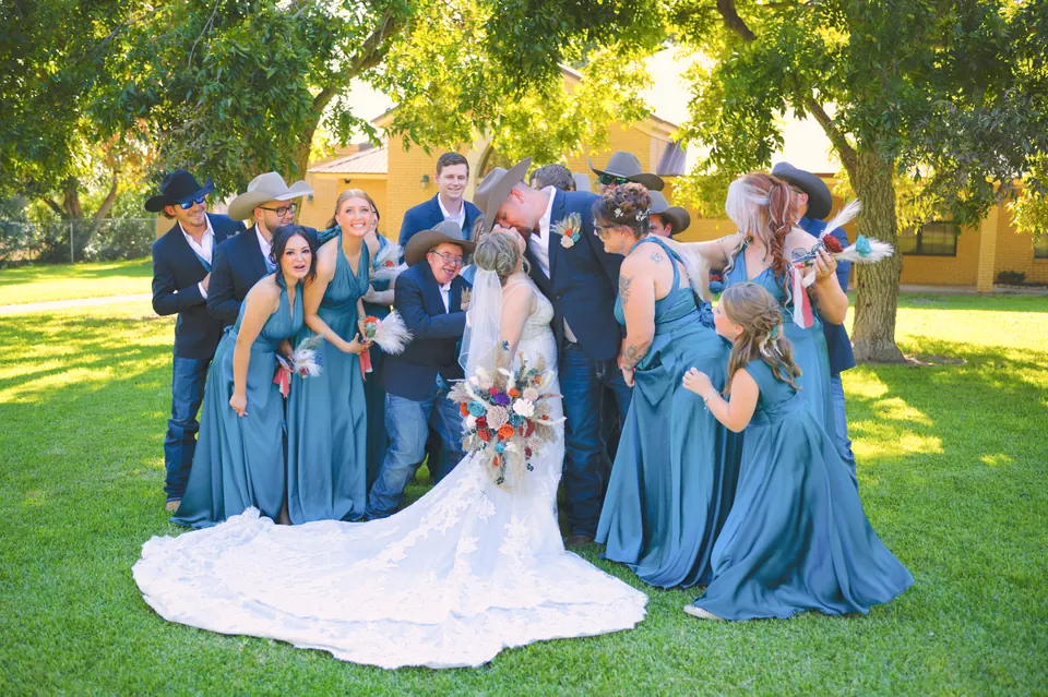 Cortejo nupcial con damas en azul polvo riendo bajo los árboles el día de la boda en Kosciusko, Texas
