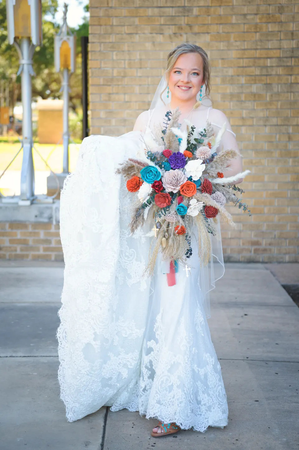 Novia con su ramo de flores secas frente a la iglesia en la Iglesia Católica St. Anne's en Kosciusko, Texas