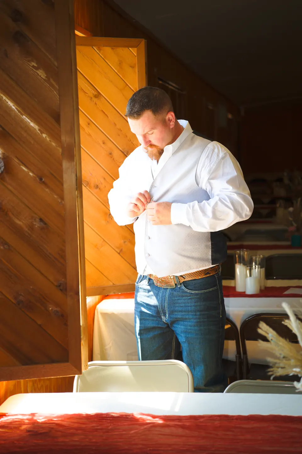 Novio abotonándose la camisa mientras se prepara para su boda en Kosciusko, Texas