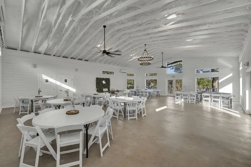 Bright reception hall with round tables and ceiling fans at The Casa at Canyon Lake
