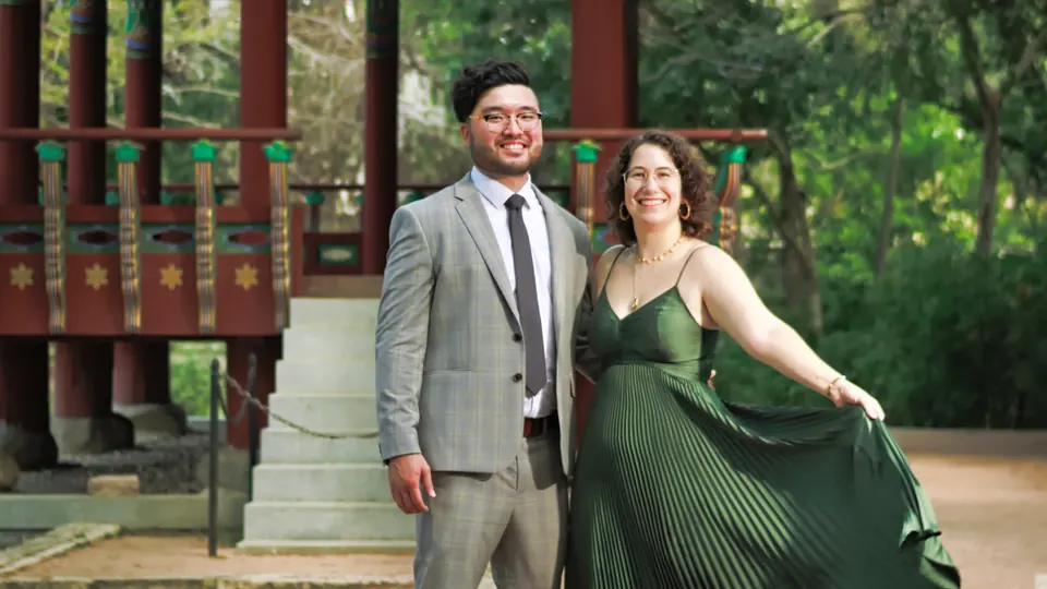 Engaged couple smiling in front of the red and green Korean Pavilion at Denman Estate Park
