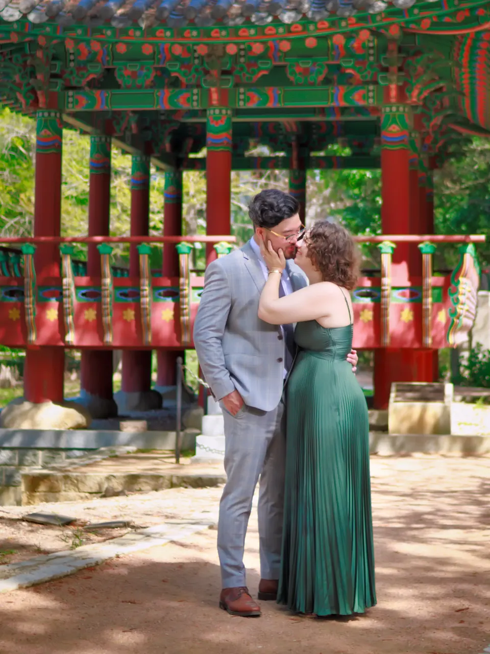 Engaged couple kissing in front of the Korean Pavilion at Denman Estate Park in San Antonio