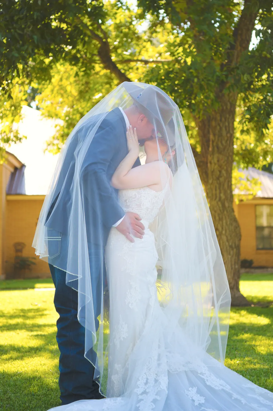 Bride and groom kissing beneath her veil under the oak trees on their Kosciusko, Texas wedding day