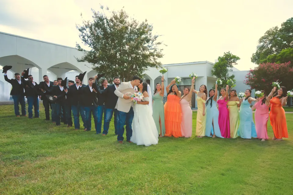 Wedding party cheering with raised hats and bouquets on the lawn in San Antonio