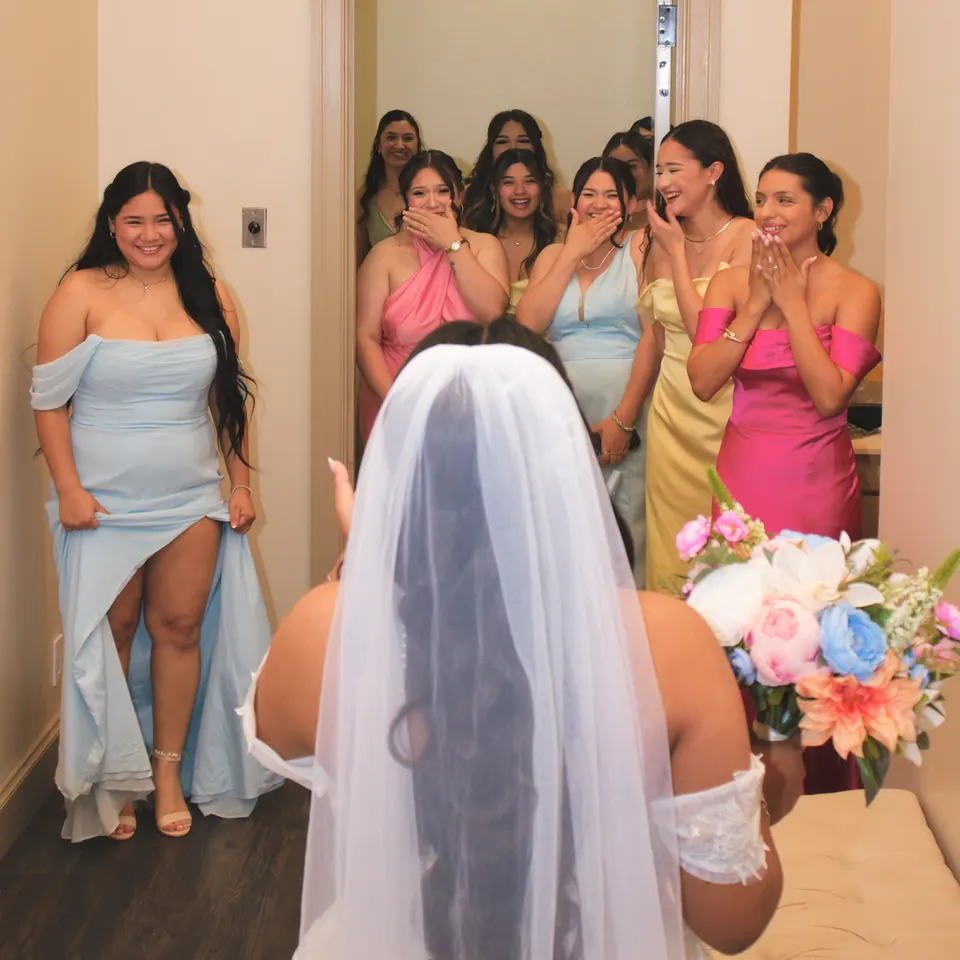 Bridesmaids in pastel gowns gasping as they see the bride for the first time at the Phoenician Ballroom Event Center in San Antonio