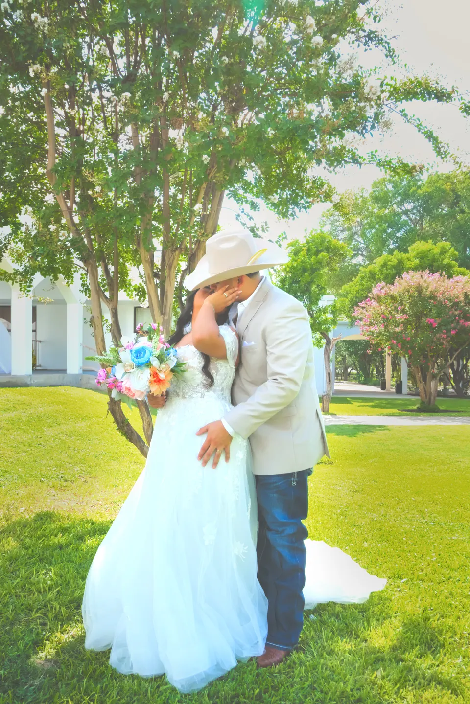 Bride with a pastel bouquet kissing the groom in a garden on their San Antonio wedding day