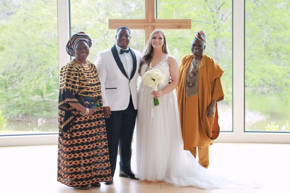 Bride and groom with family in traditional Nigerian attire in front of the cross window at The Preserve at Canyon Lake chapel