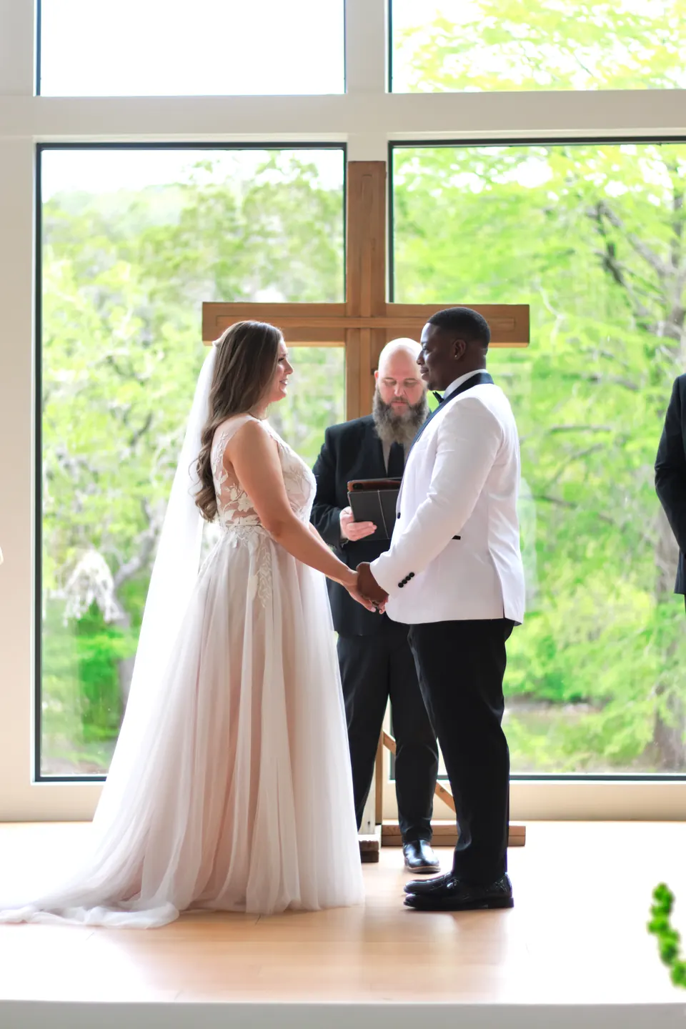 Bride and groom holding hands during vows before the cross window at The Preserve at Canyon Lake chapel