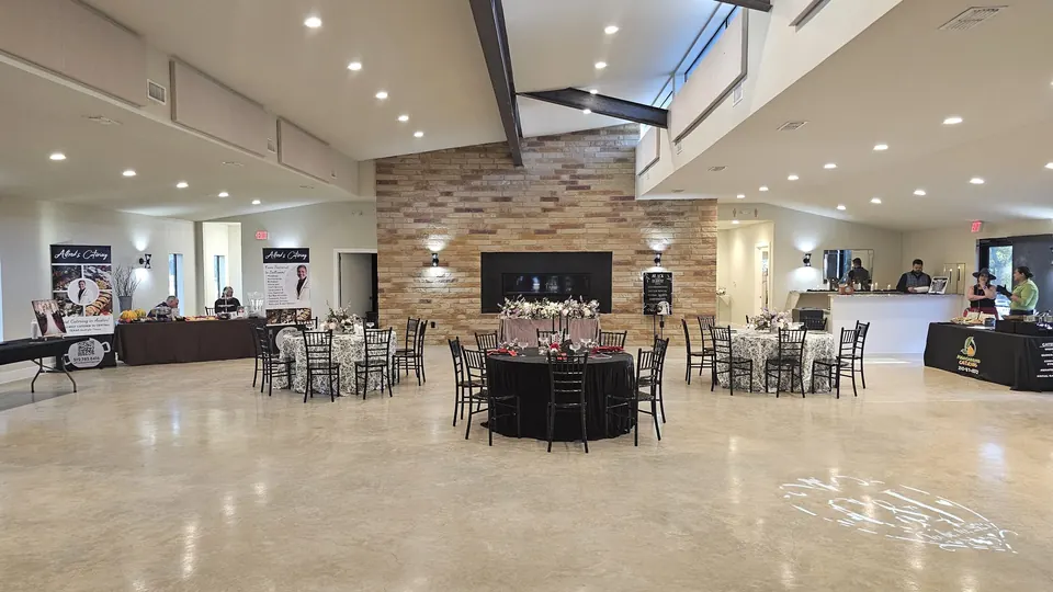 Spacious main reception hall with a stone feature wall, vaulted ceiling and set tables at Prima Vista in Wimberley, Texas