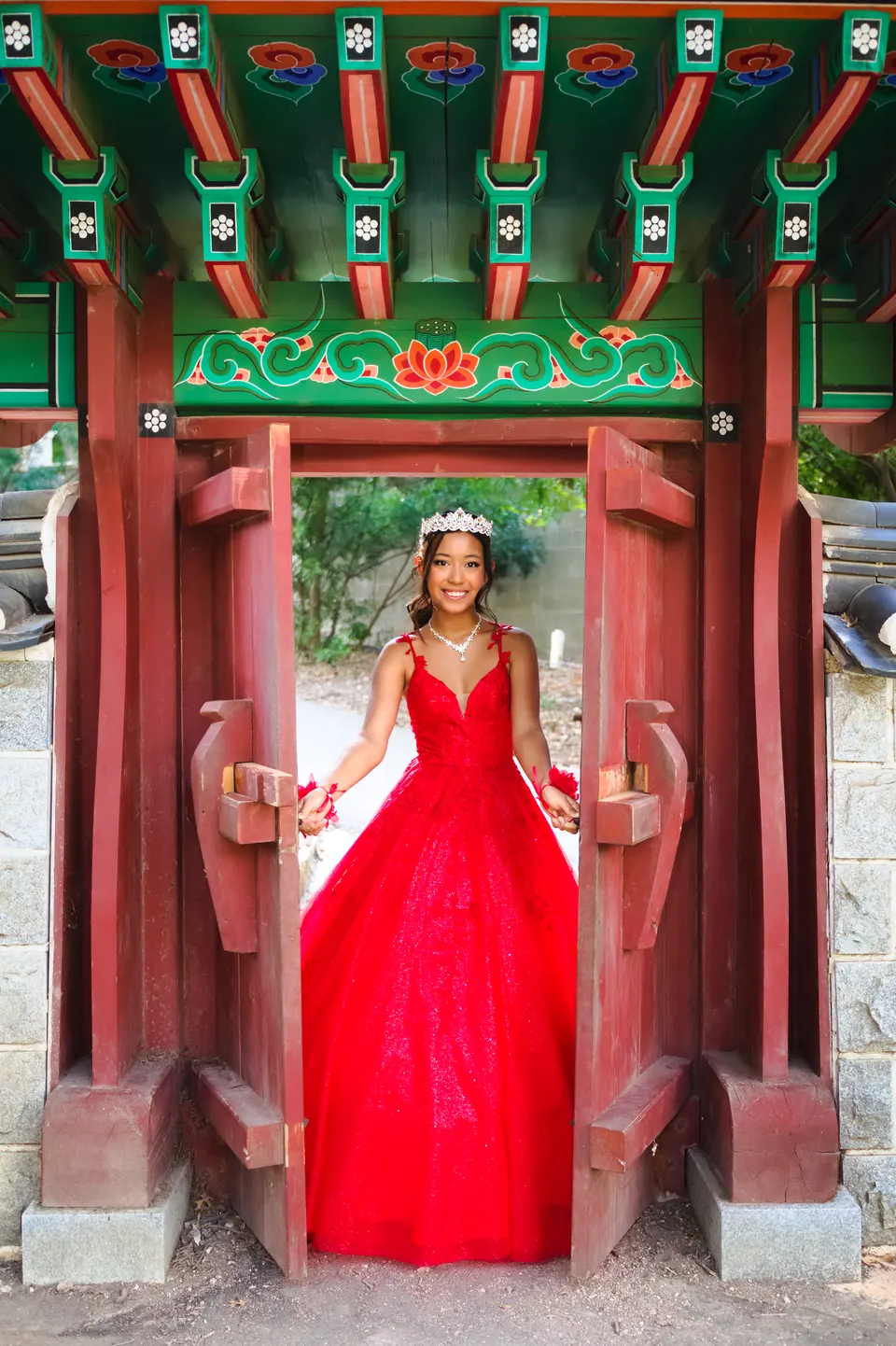 Quinceañera enmarcada por la puerta pintada del pabellón coreano en Denman Estate Park, San Antonio