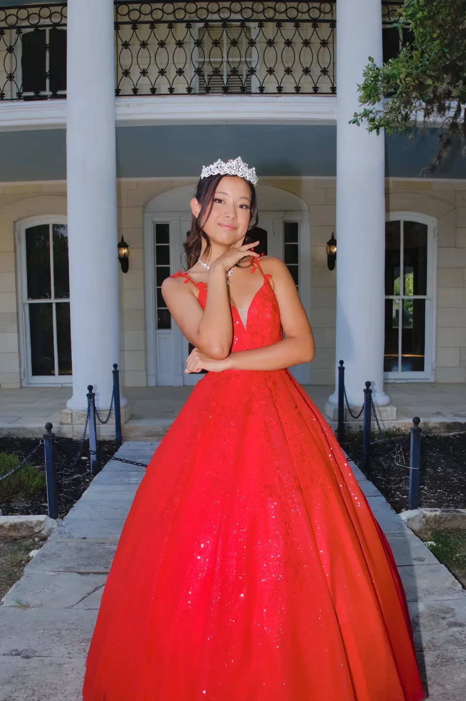 Quinceañera posando entre columnas blancas con su vestido de XV años en Denman Estate Park, San Antonio