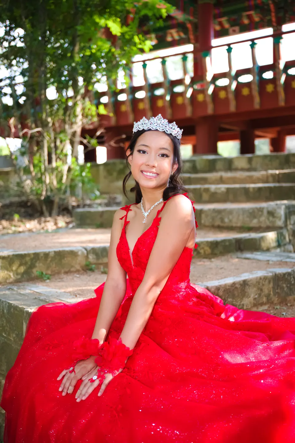 Quinceañera sentada en los escalones de piedra cerca del pabellón coreano en Denman Estate Park, San Antonio