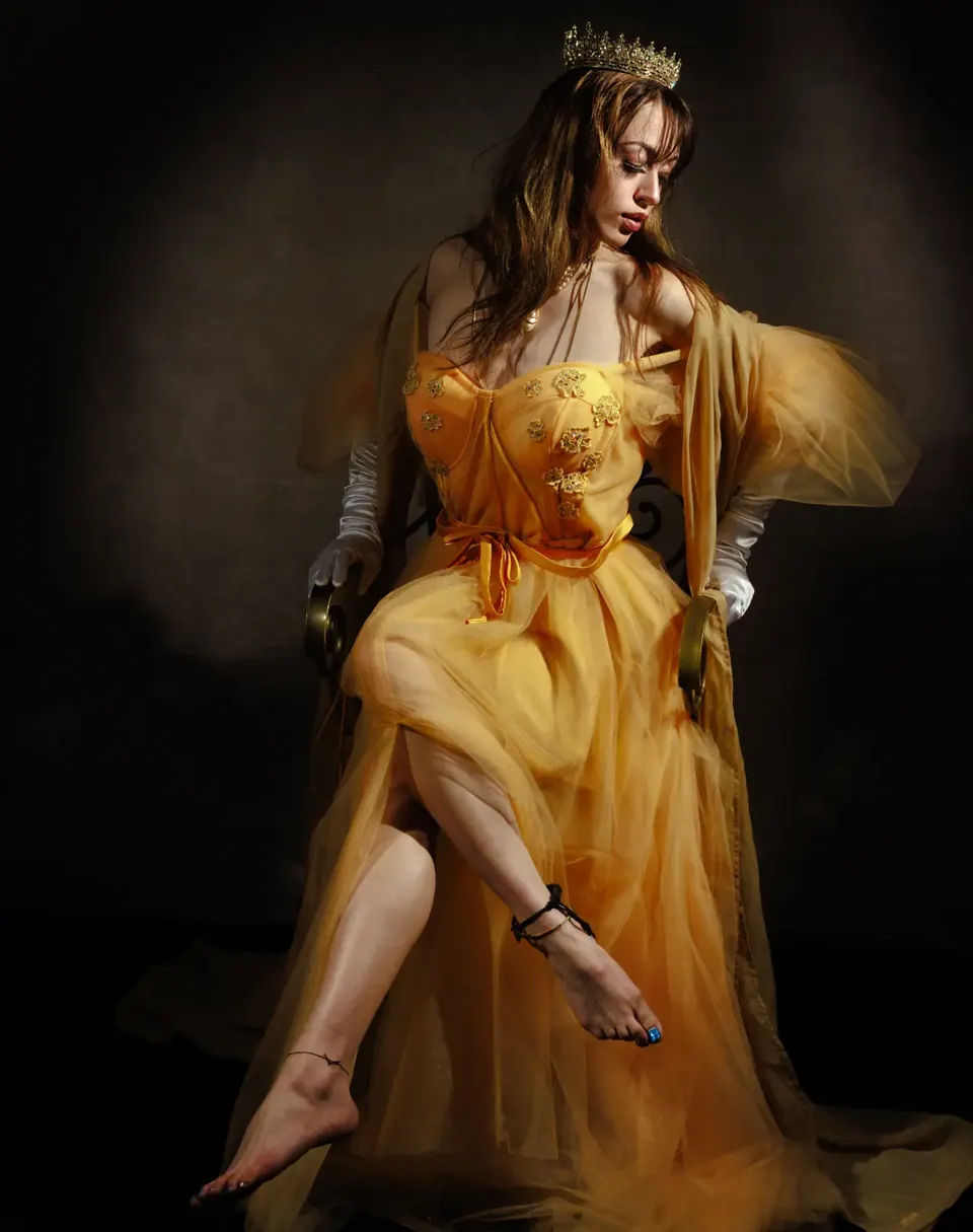 Creative studio portrait of a woman in a flowing gold gown and crown in San Antonio