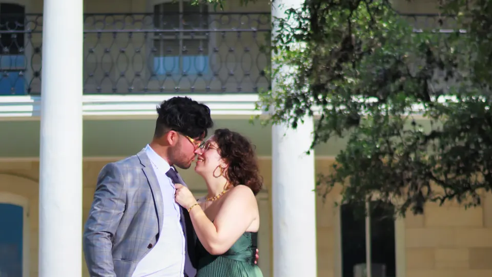 Close-up of an engaged couple kissing between white columns in San Antonio