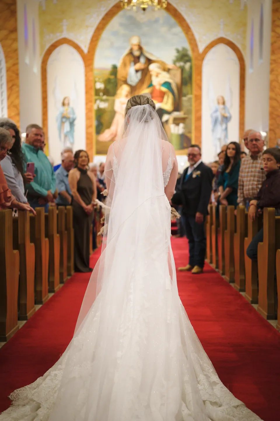 Bride walking down the red-carpet aisle toward the altar at St. Anne's Catholic Church in Kosciusko, Texas