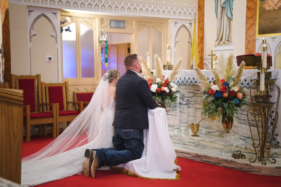 Bride and groom kneeling at the altar during the wedding Mass at St. Anne's Catholic Church in Kosciusko, Texas